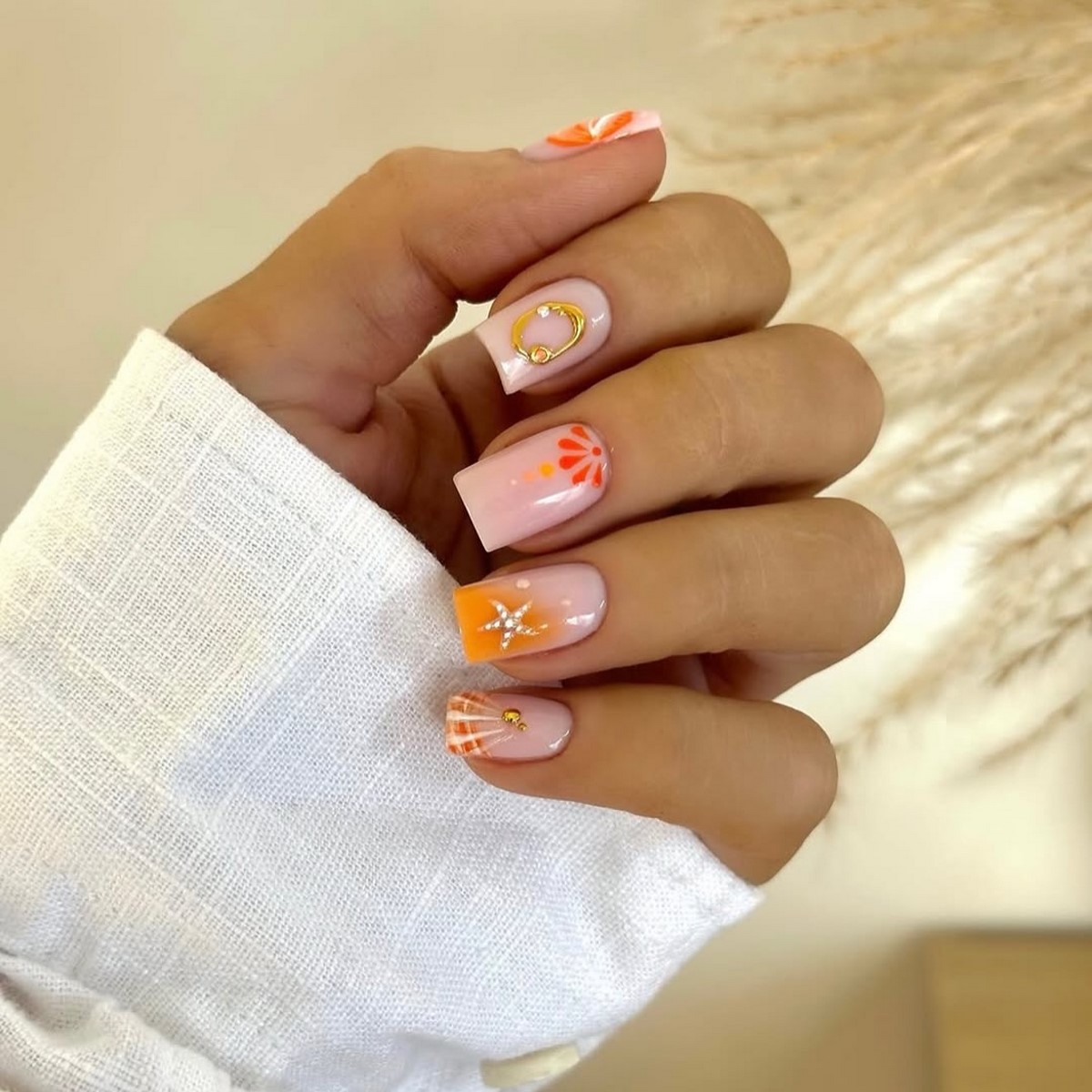 Розово-оранжевый маникюр с геометрическими линиями, цветочными мотивами и золотыми деталями
