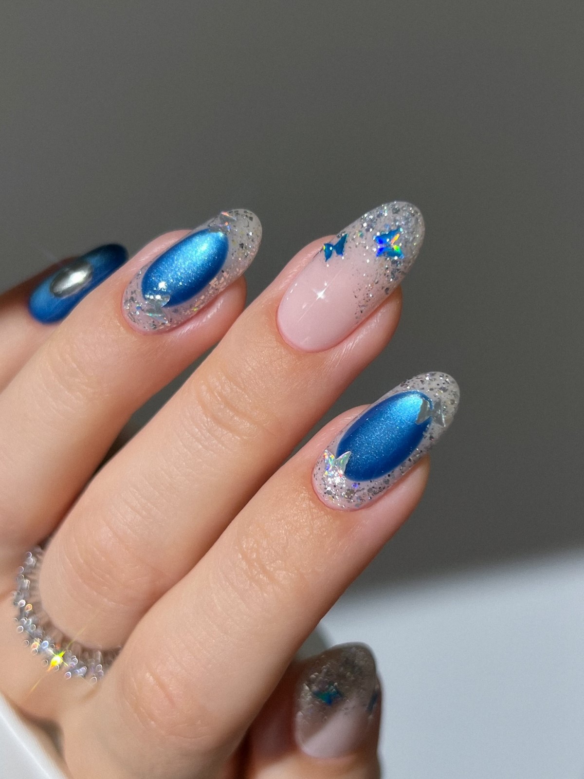 Синий маникюр с cat-eye эффектом, серебристым блеском и маленькими бабочками