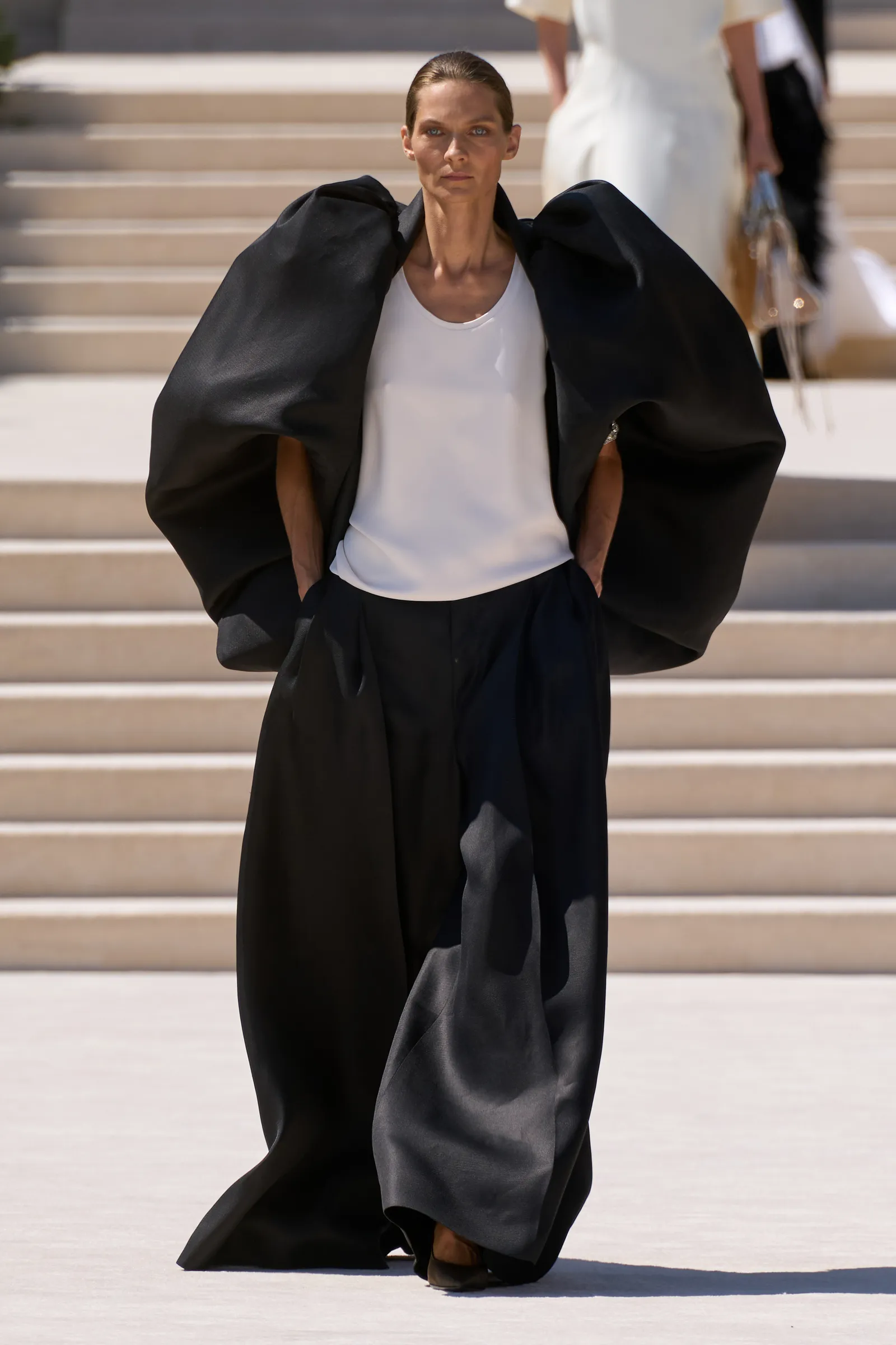 Balenciaga couture: черный объемный кейп поверх белого топа и широких брюк