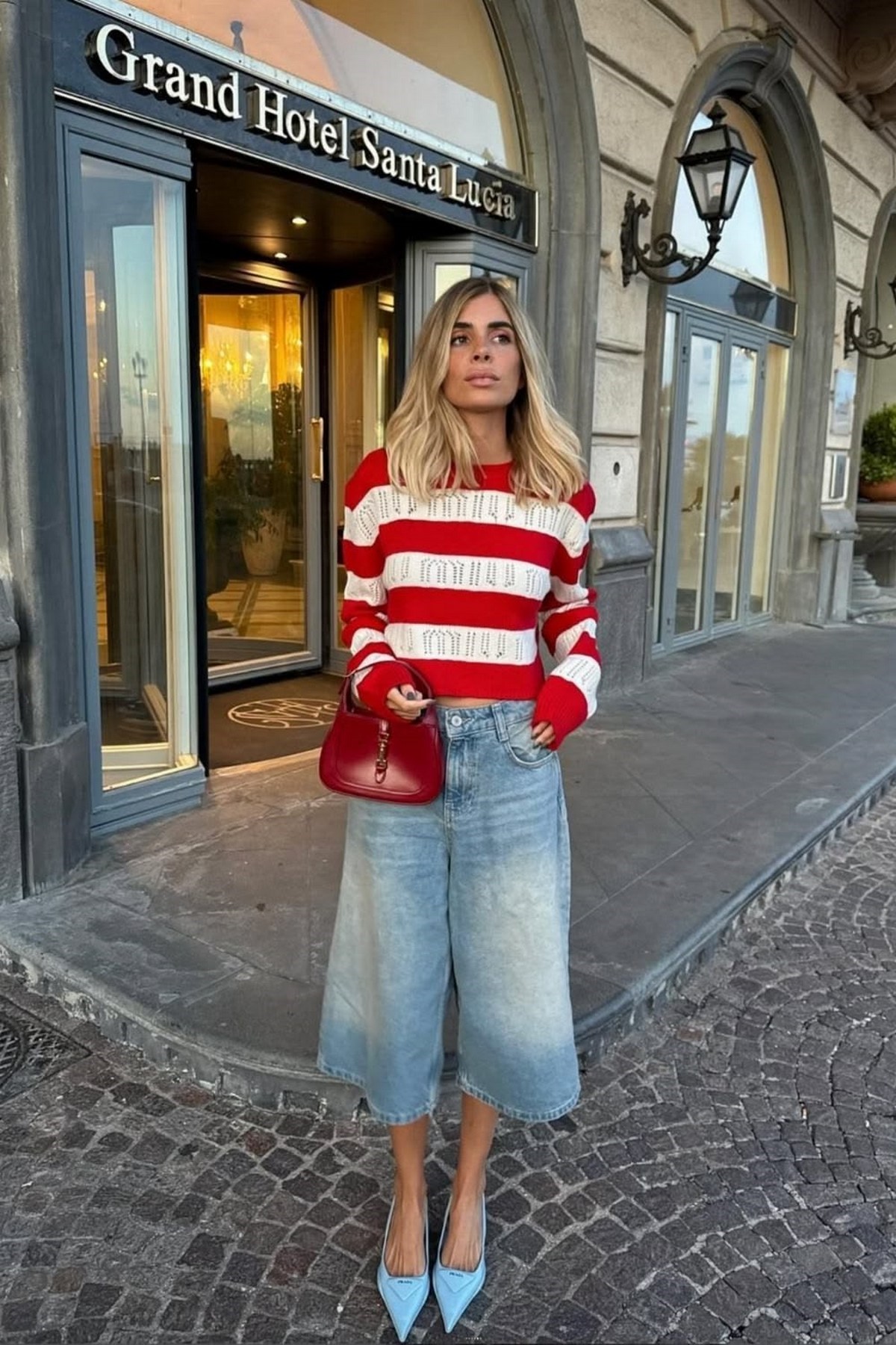 Женщина в широких джинсовых шортах jorts, полосатом джемпере и голубых туфлях с острым мысом