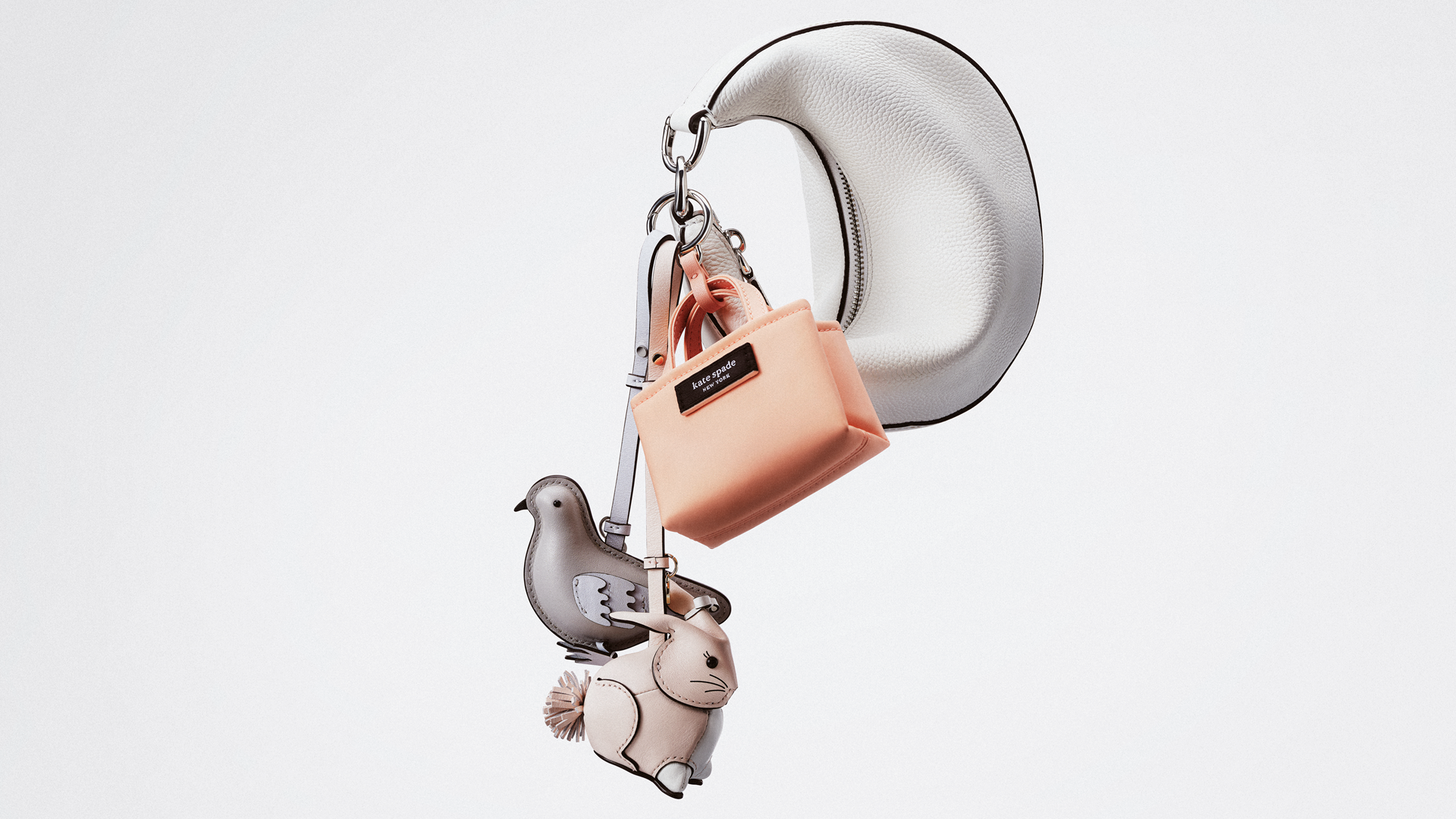 Белая сумка Kate Spade с миниатюрной розовой сумкой и фигурными подвесками