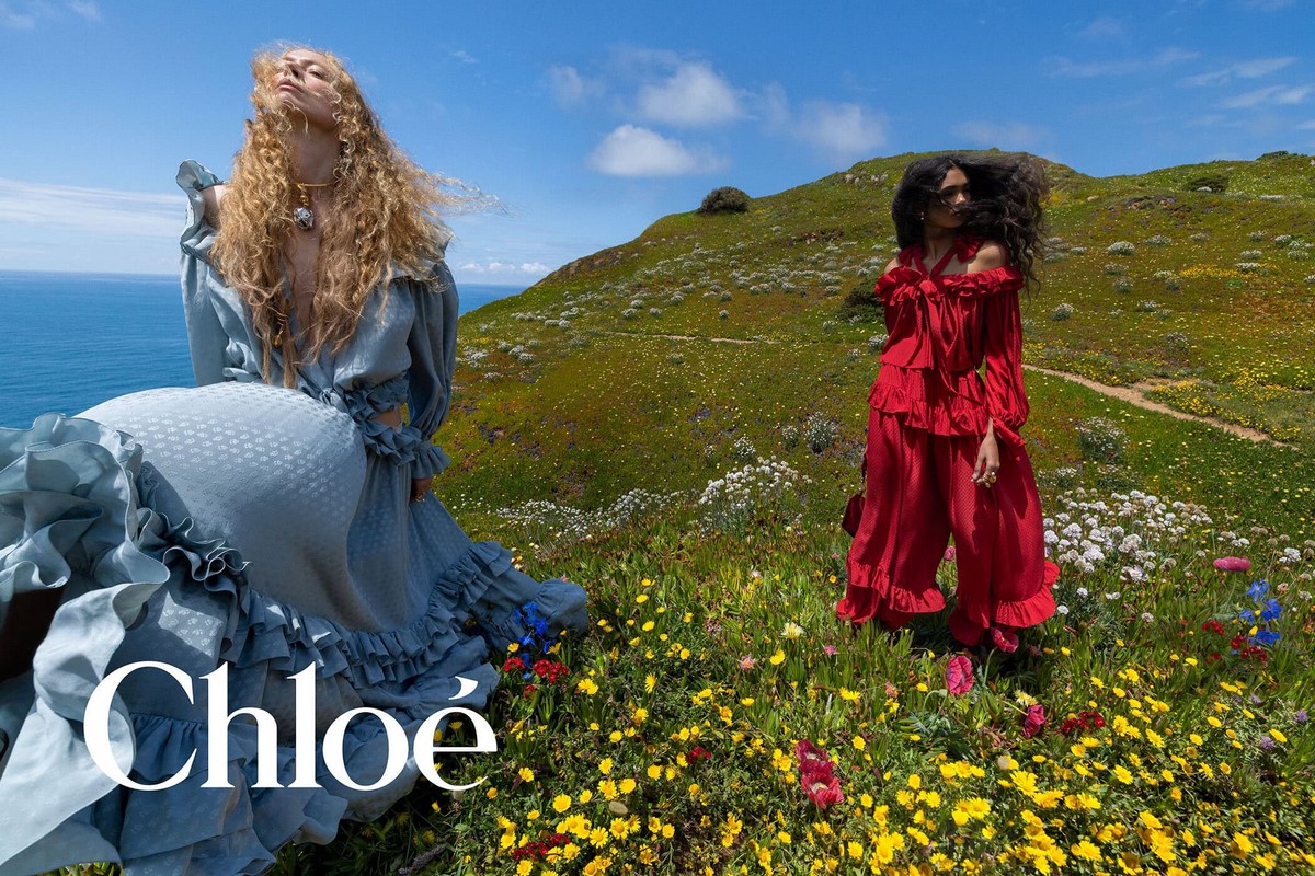 Голубой объемный силуэт и красный комплект Chloé среди цветущего поля