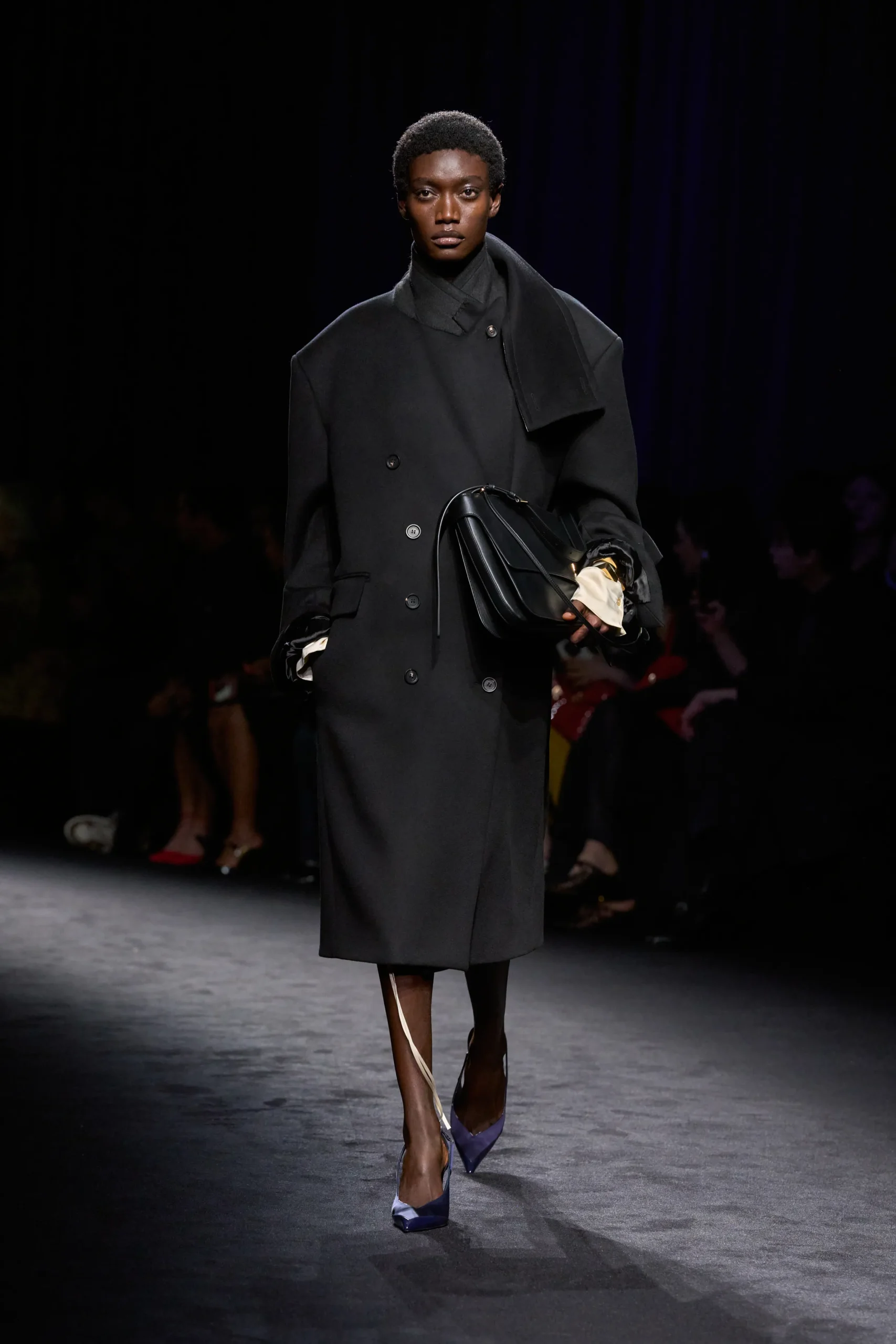 Модель в черном пальто с асимметричным воротником на показе Ferragamo