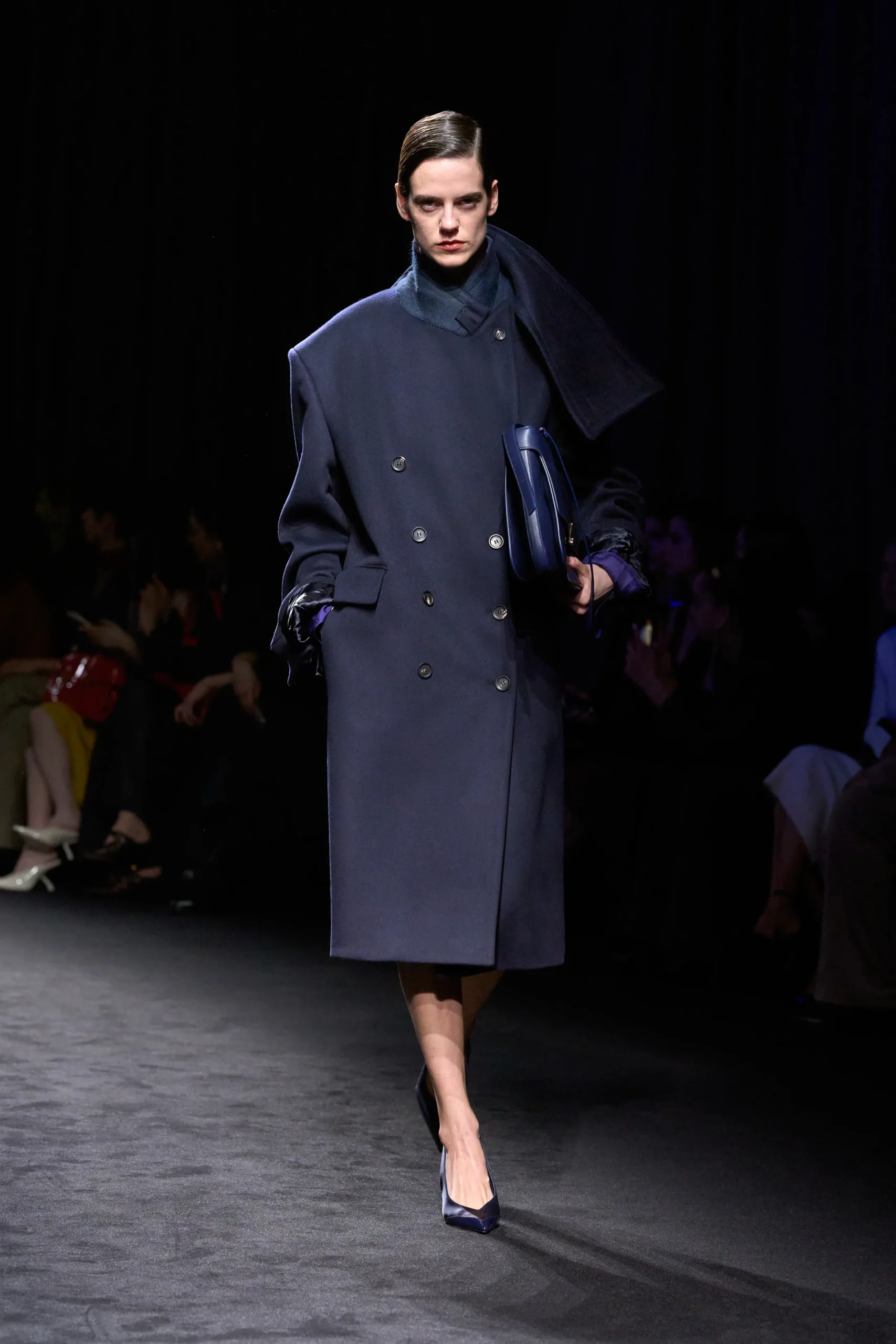 Модель в темно-синем двубортном пальто с асимметричным воротником на показе Ferragamo