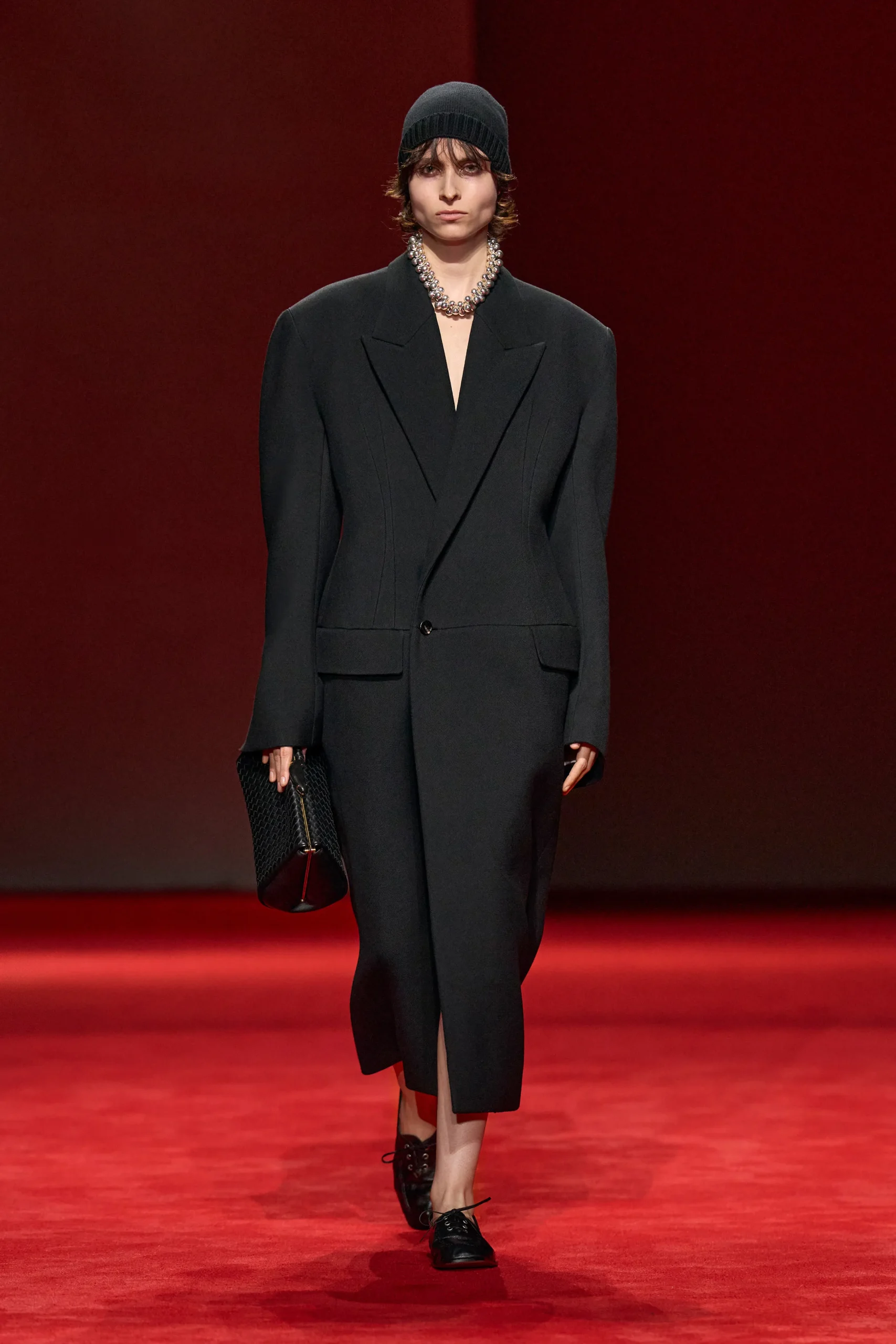 Черное скульптурное пальто Bottega Veneta на красном подиуме