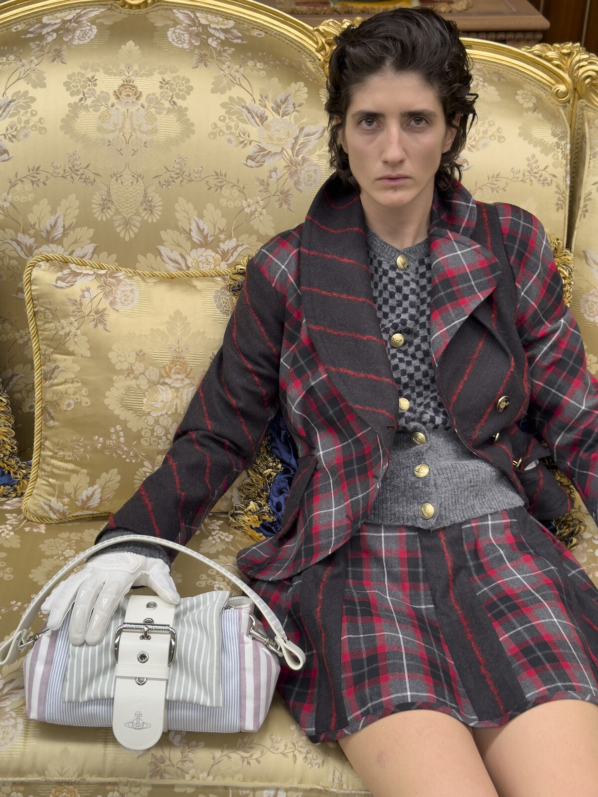 Модель в клетчатом костюме Vivienne Westwood на диване с золотой обивкой